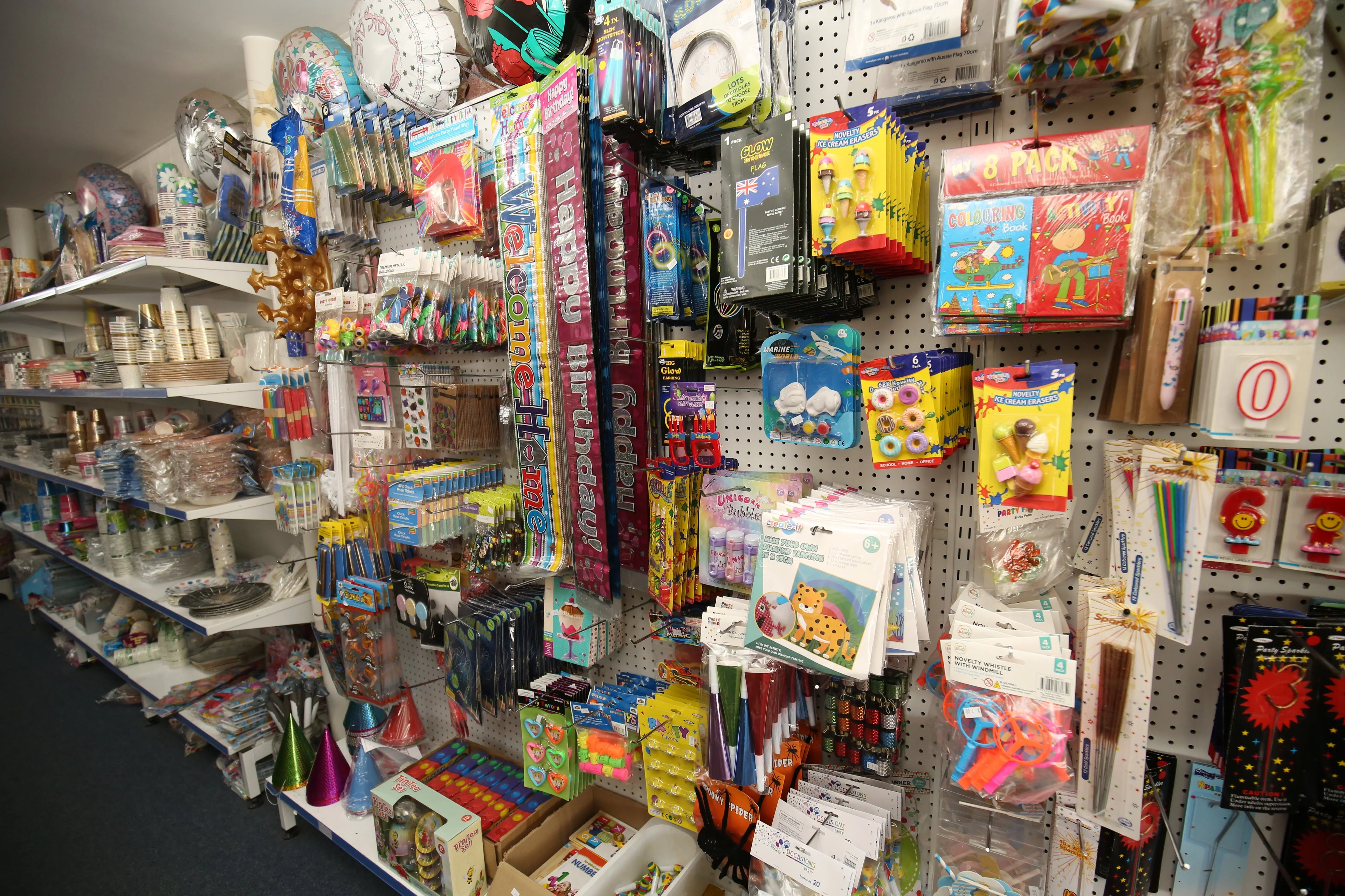 Retail display of party supplies, colorful tableware, and celebration accessories on shelves.
