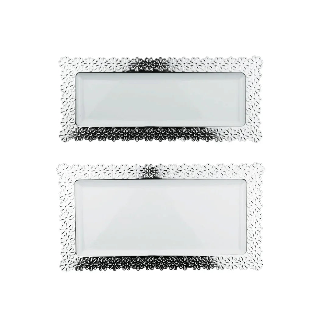 Two rectangular silver decorative trays with floral embossed borders and white inserts.