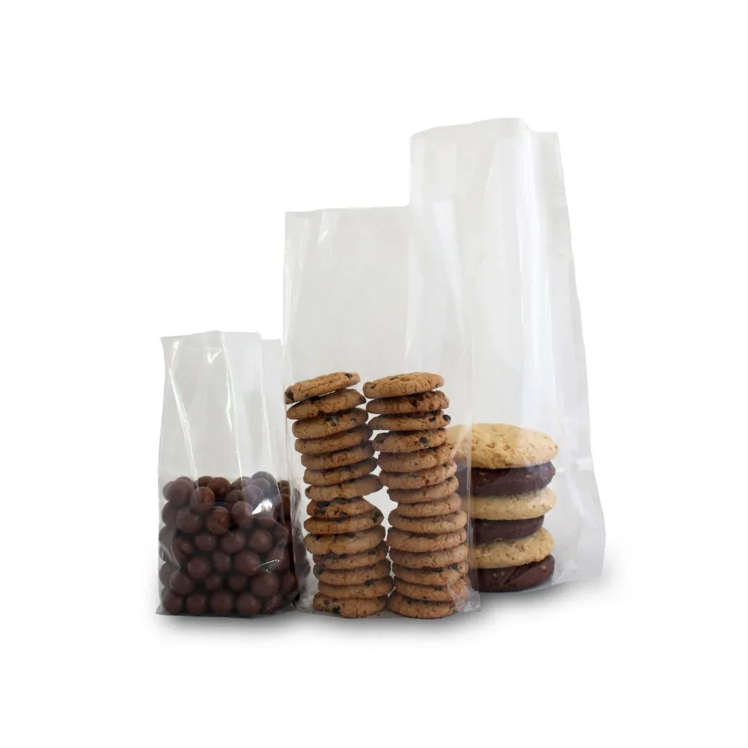 Three clear plastic treat bags filled with chocolate balls, chocolate chip cookies, and sandwich cookies.
