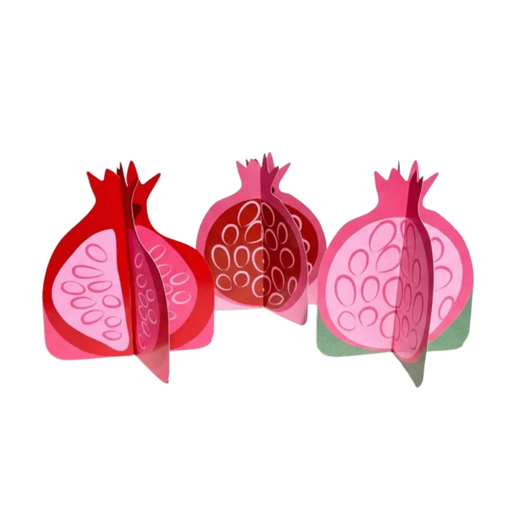 Three 3D paper pomegranate decorations in shades of red and pink