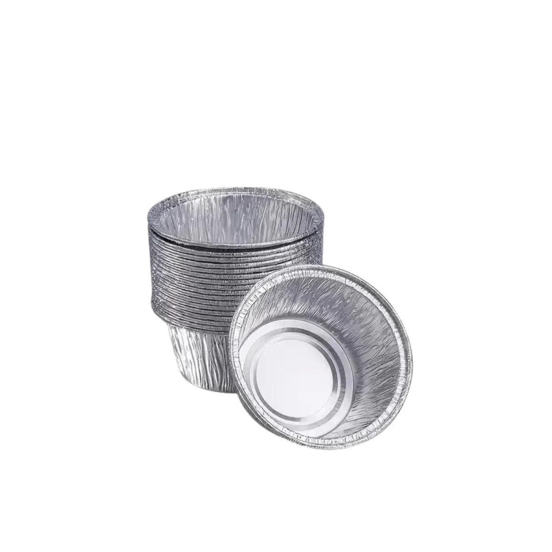 Stack of disposable aluminium foil cupcake liners and one tilted liner on a white background