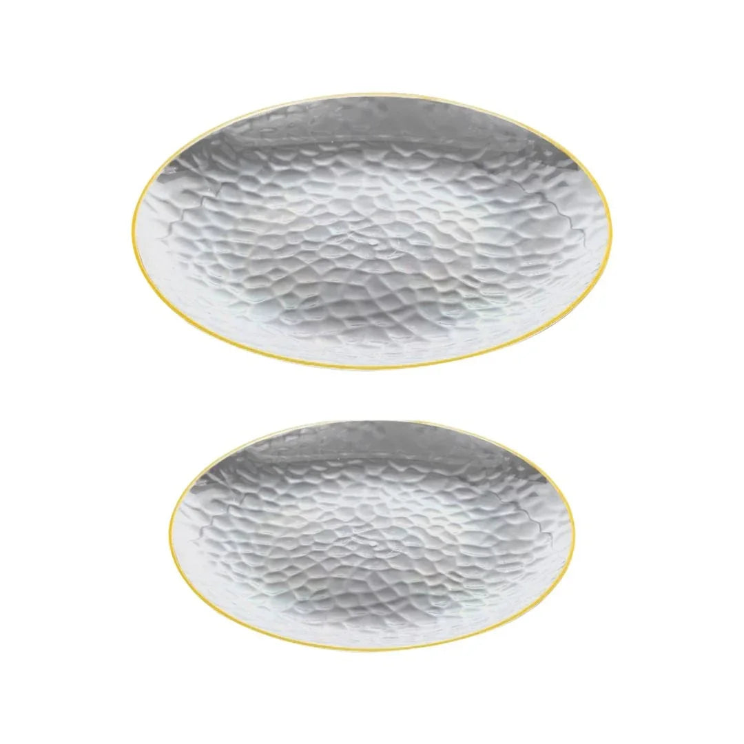 Two oval hammered silver platters with gold rims