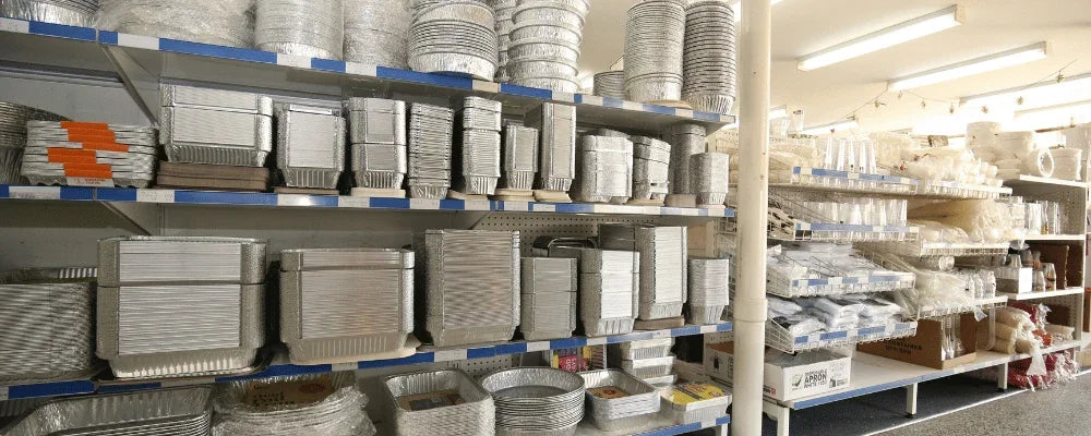 Assorted aluminum foil catering trays and food containers on store shelves.